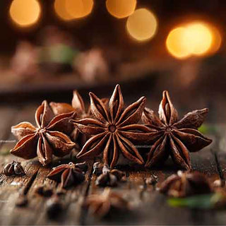  Un'immagine ravvicinata di stelle di anice essiccate (Illicium verum) su un tavolo di legno, con luci calde sfocate sullo sfondo. Questa scena cattura la bellezza e l'aroma speziato dell'anice stellato biologico.